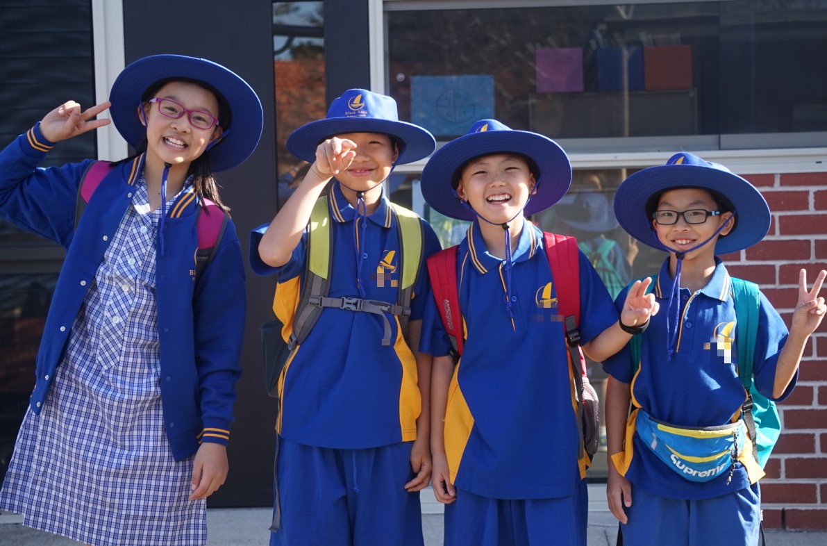 4 kids in purple school uniform smiling at the camera